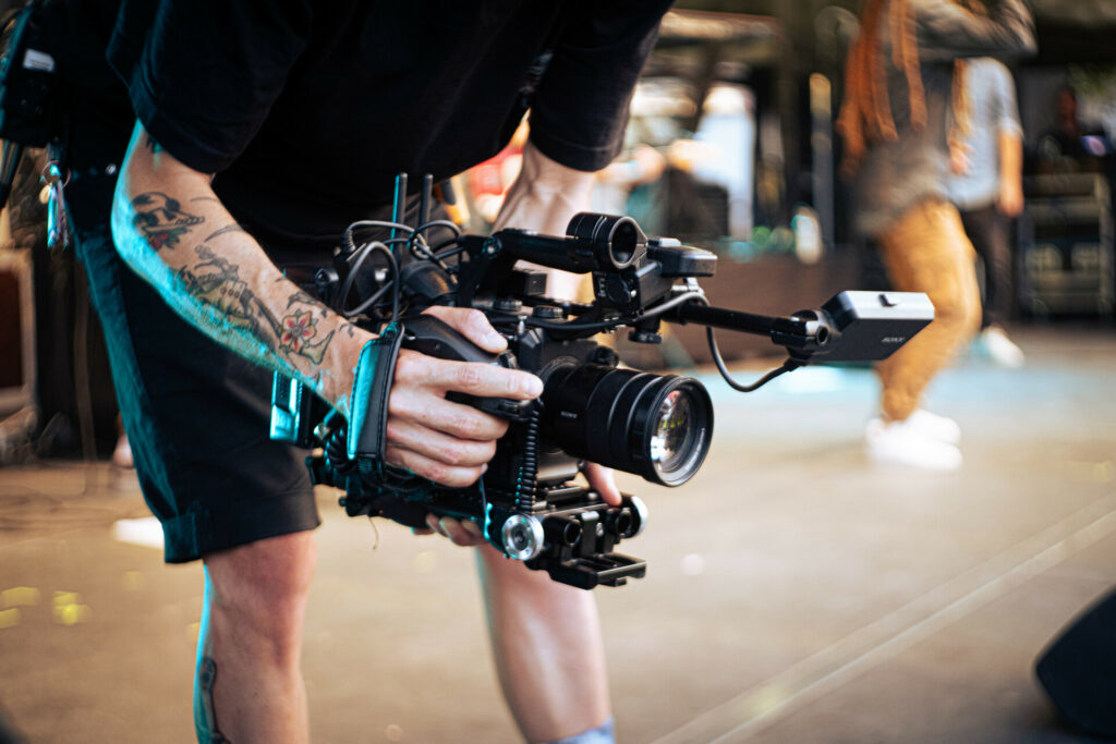 Une caméra de reportage professionnelle tenue par un cadreur en train de filmer.